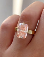 Top-down view of a stunning 3 ct pink elongated radiant cut lab diamond solitaire ring worn on a finger.
