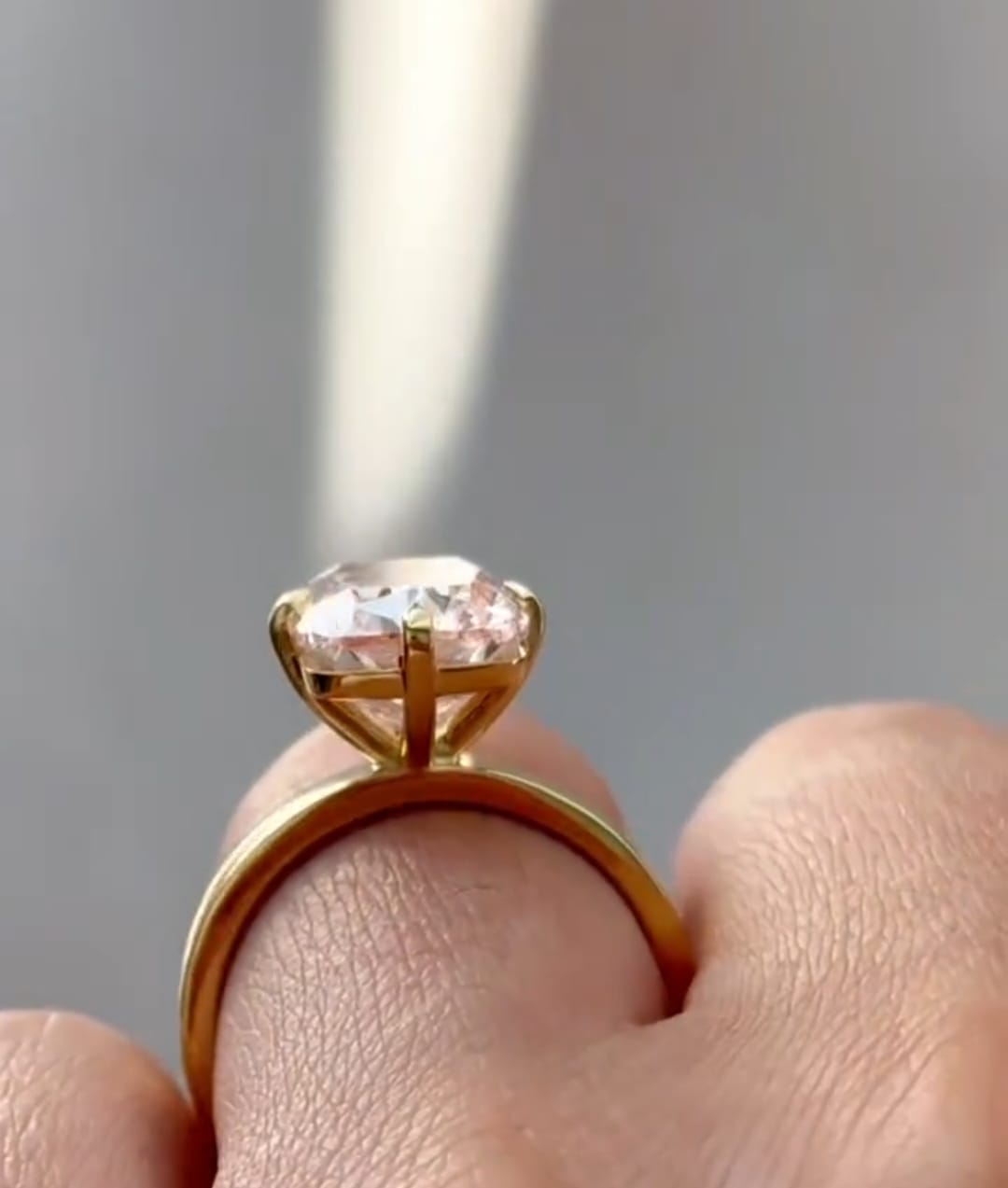 Side profile view of a yellow gold 4-prong solitaire setting holding a large radiant cut fancy color lab diamond.