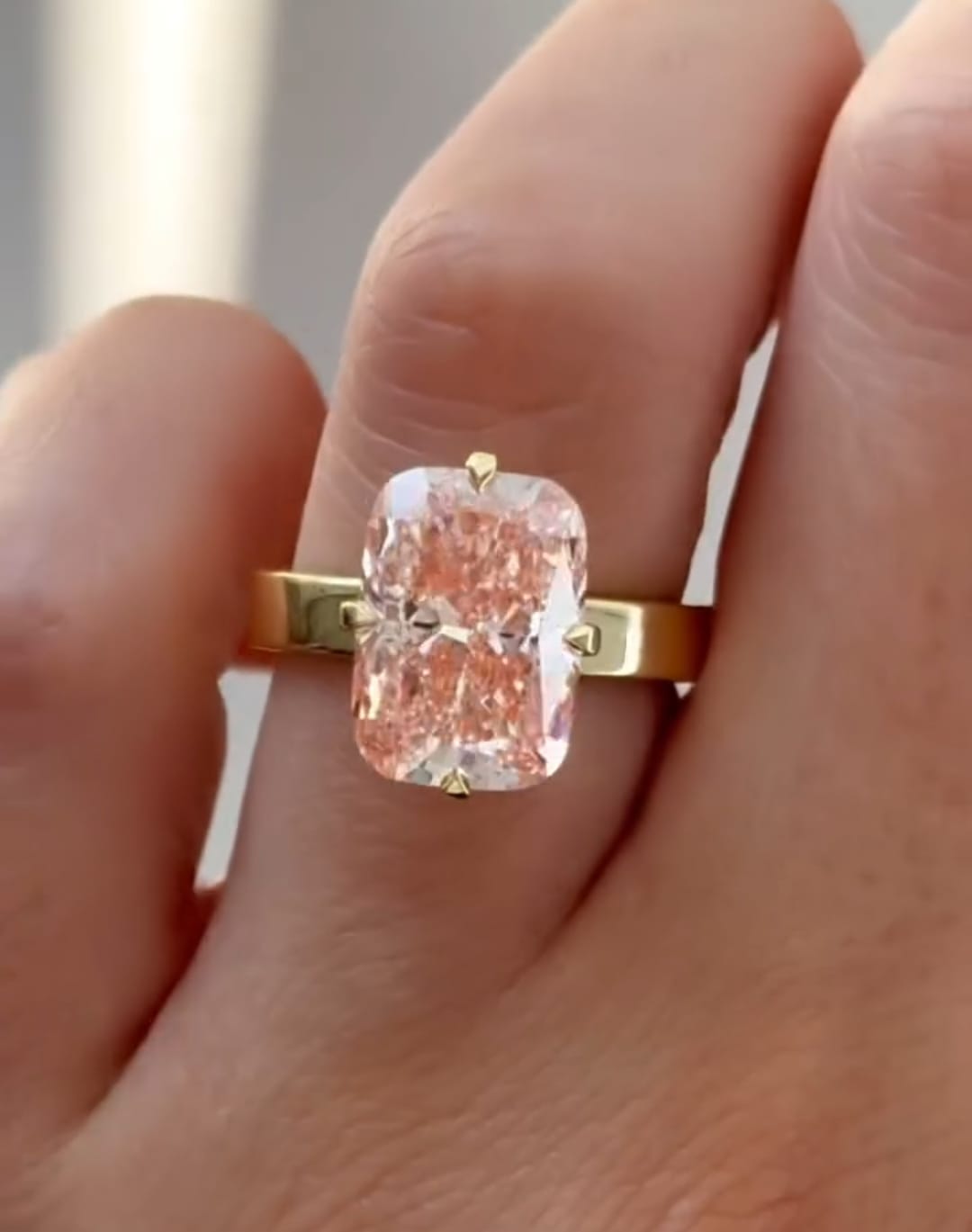 Direct front view of a vibrant 3 carat pink radiant lab grown diamond sparkling in a classic yellow gold solitaire setting.