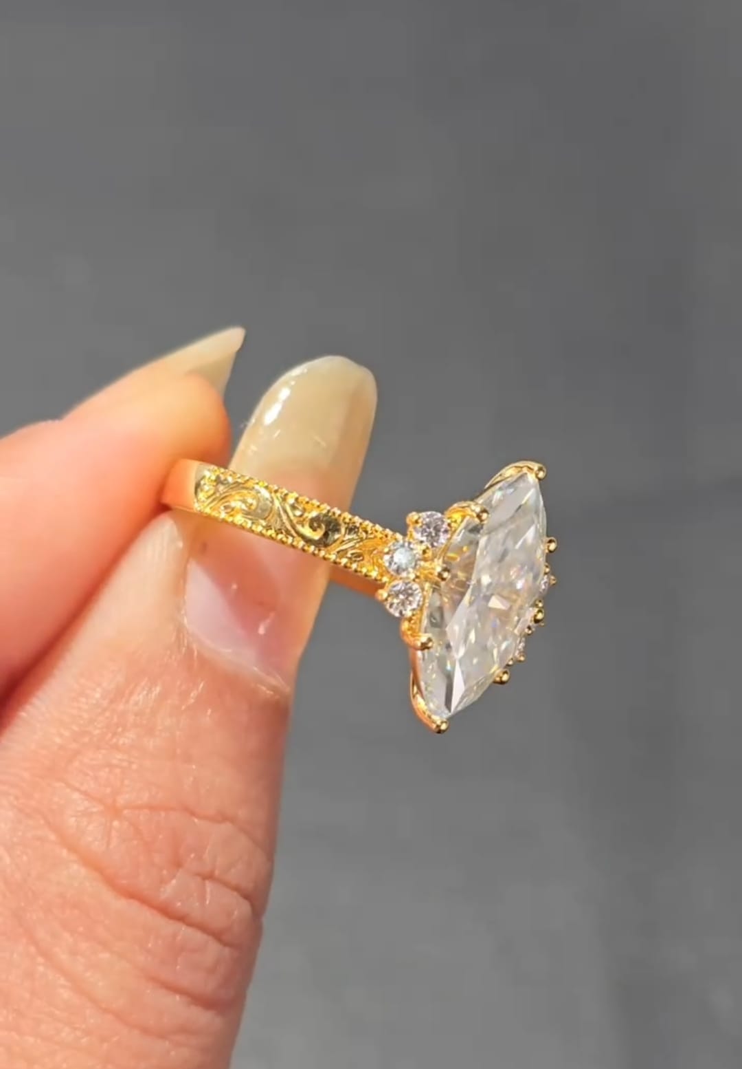 Close-up side profile of a 3 carat marquise lab grown diamond ring showing intricate vintage scroll engraving on a yellow gold band.