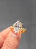 Top-down view of a 3 CT marquise cut engagement ring featuring round diamond side stones in a yellow gold setting.