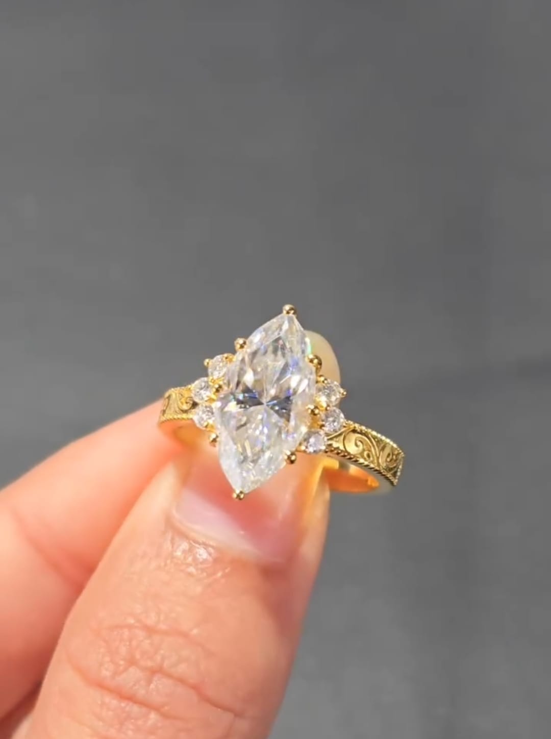 Top-down view of a 3 CT marquise cut engagement ring featuring round diamond side stones in a yellow gold setting.