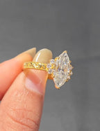 Close-up angled top view of a brilliant 3 carat marquise lab diamond engagement ring with diamond cluster accents.