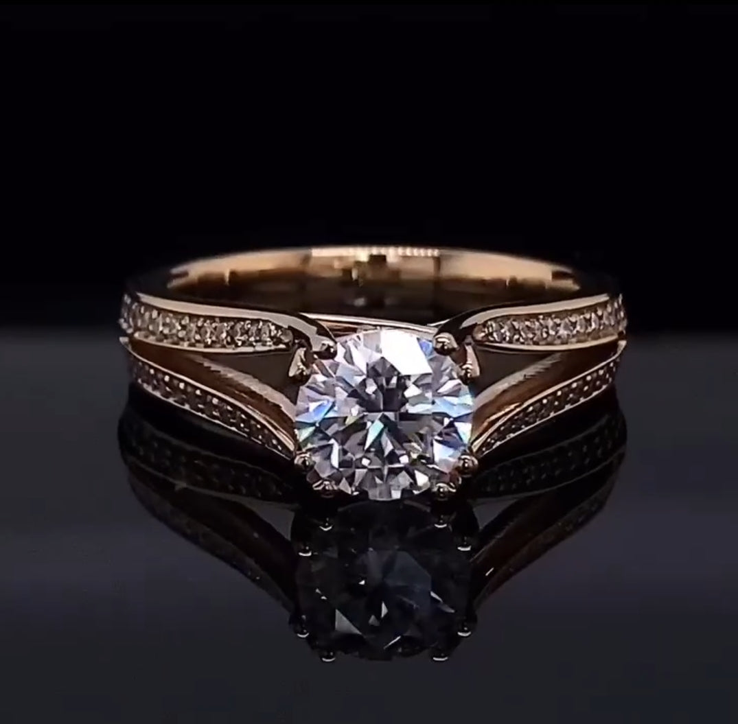 Front view of a 2 carat round cut lab grown diamond engagement ring featuring a twisted diamond pavé split shank on a reflective black background.