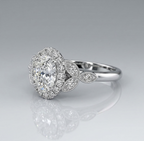 Angled rear profile of an oval diamond engagement ring highlighting the vintage-inspired leaf motif shoulders with delicate milgrain detailing.