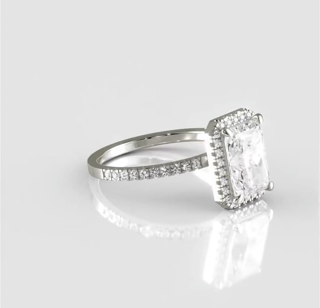 Angled top view of a radiant cut diamond engagement ring highlighting its elongated rectangular shape, delicate pavé halo, and brilliant facets.