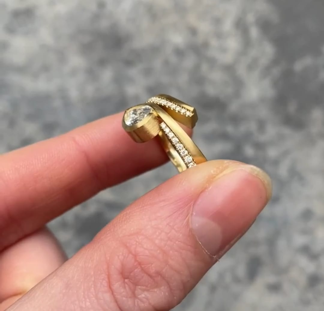 Side profile view of a yellow gold 2 CT Pear Cut Lab Grown Diamond bezel ring showing the modern open wrap design.