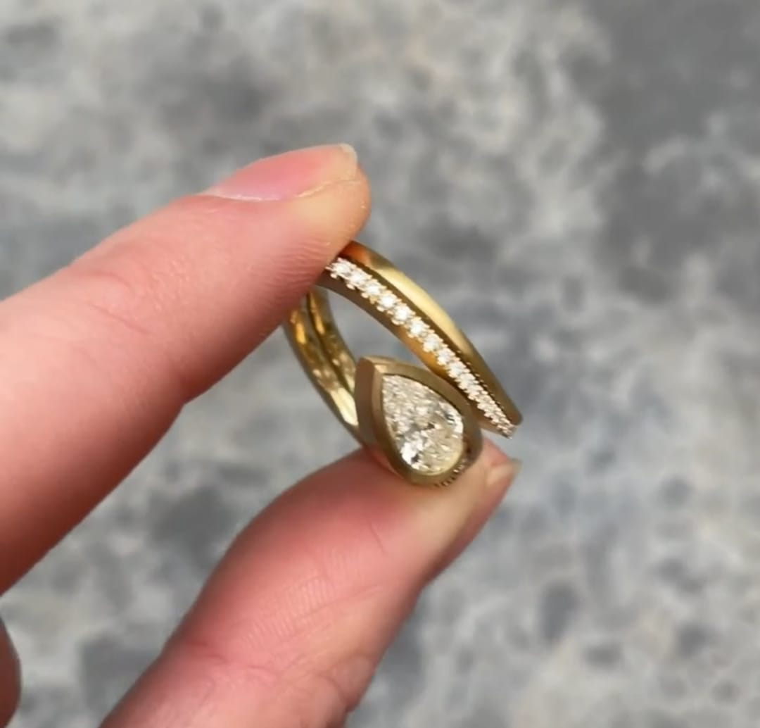Front view of the beautifully nested 2 CT Pear Lab Grown Diamond Engagement Ring set resting on fingers.