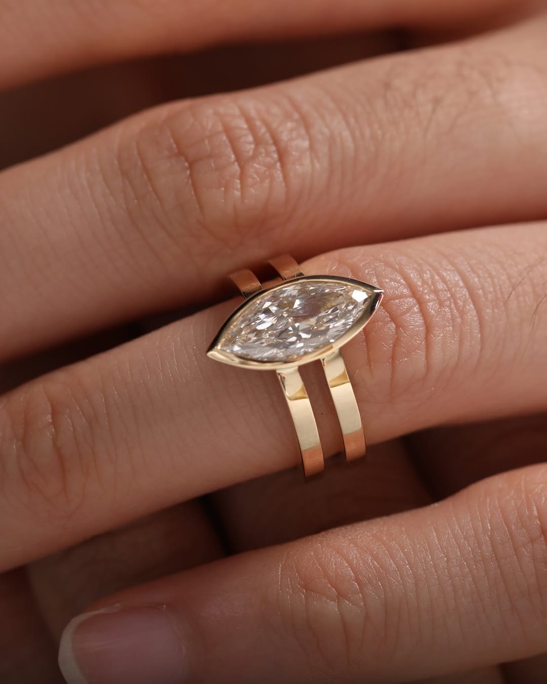 Close-up of an East-West bezel set lab grown diamond engagement ring worn on a finger.