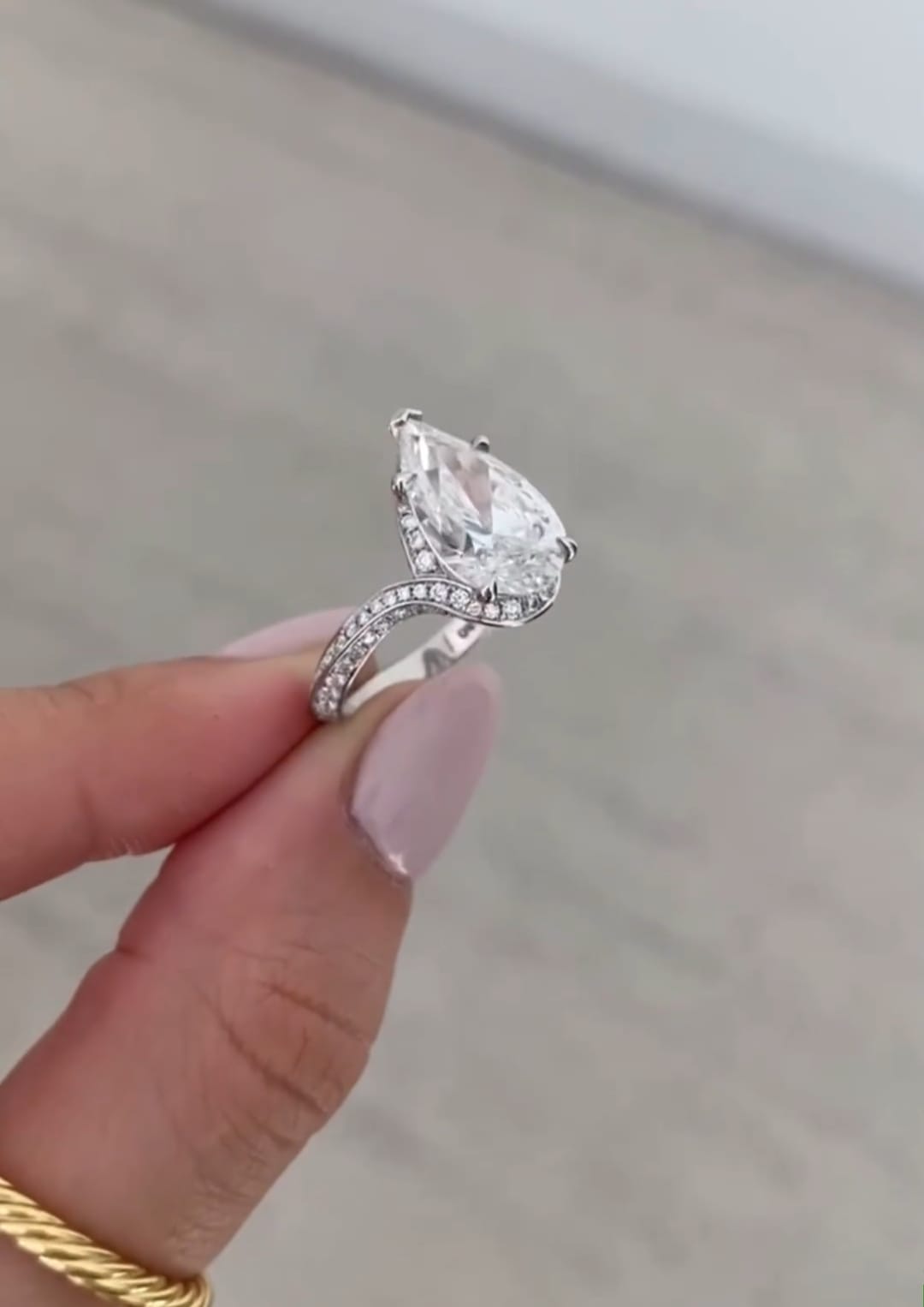 Side profile of a 4 carat pear cut lab grown diamond engagement ring with a sweeping pavé band.