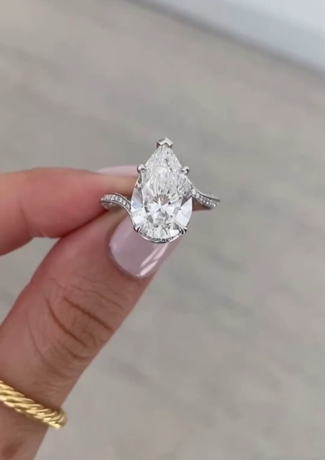 Front view of a 4 carat pear cut lab diamond ring showcasing the curved diamond band.