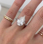 Top-down view of a massive 4 CT pear shaped lab grown diamond ring sparkling on a finger.