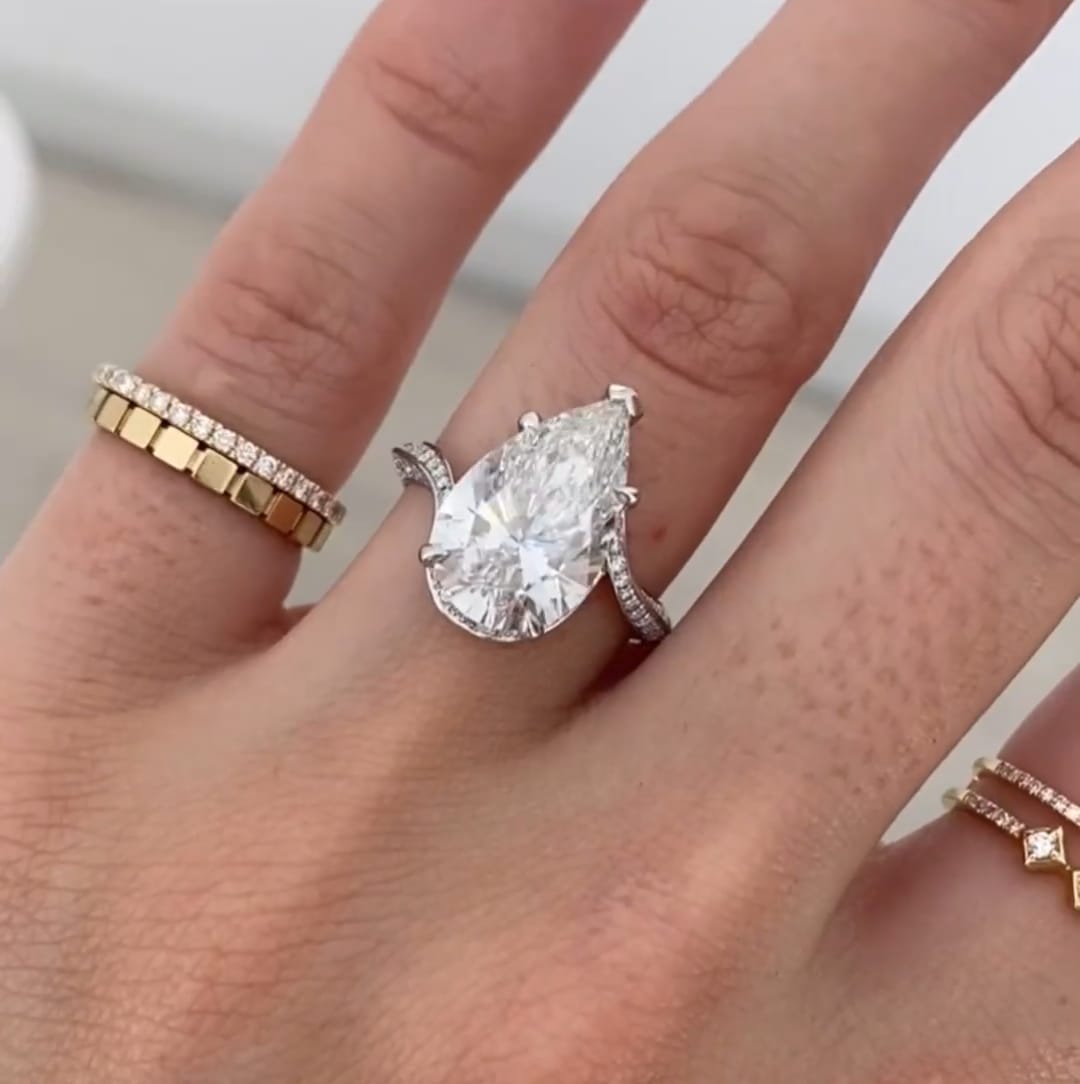 Top-down view of a massive 4 CT pear shaped lab grown diamond ring sparkling on a finger.