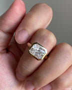 On-finger view of a sleek east-west bezel set 3 CT radiant cut lab diamond engagement ring in yellow gold.