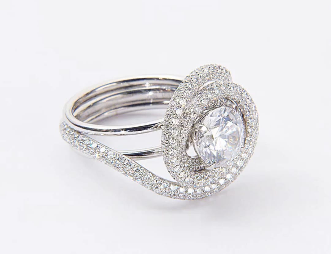 Perspective view of round lab diamond statement ring featuring swirl halo and pave band