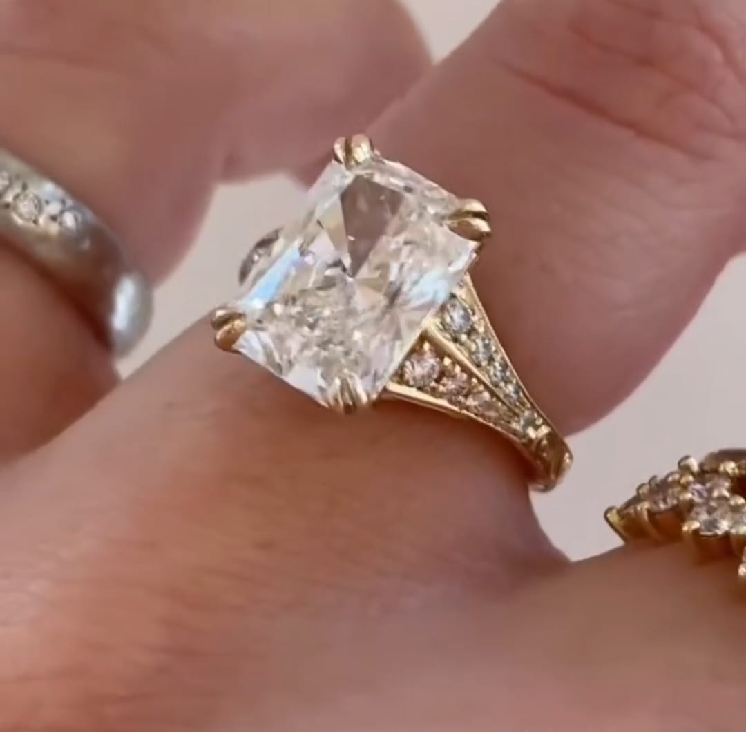 Top side view of 4 carat radiant cut lab created diamond ring on hand with pave split band.