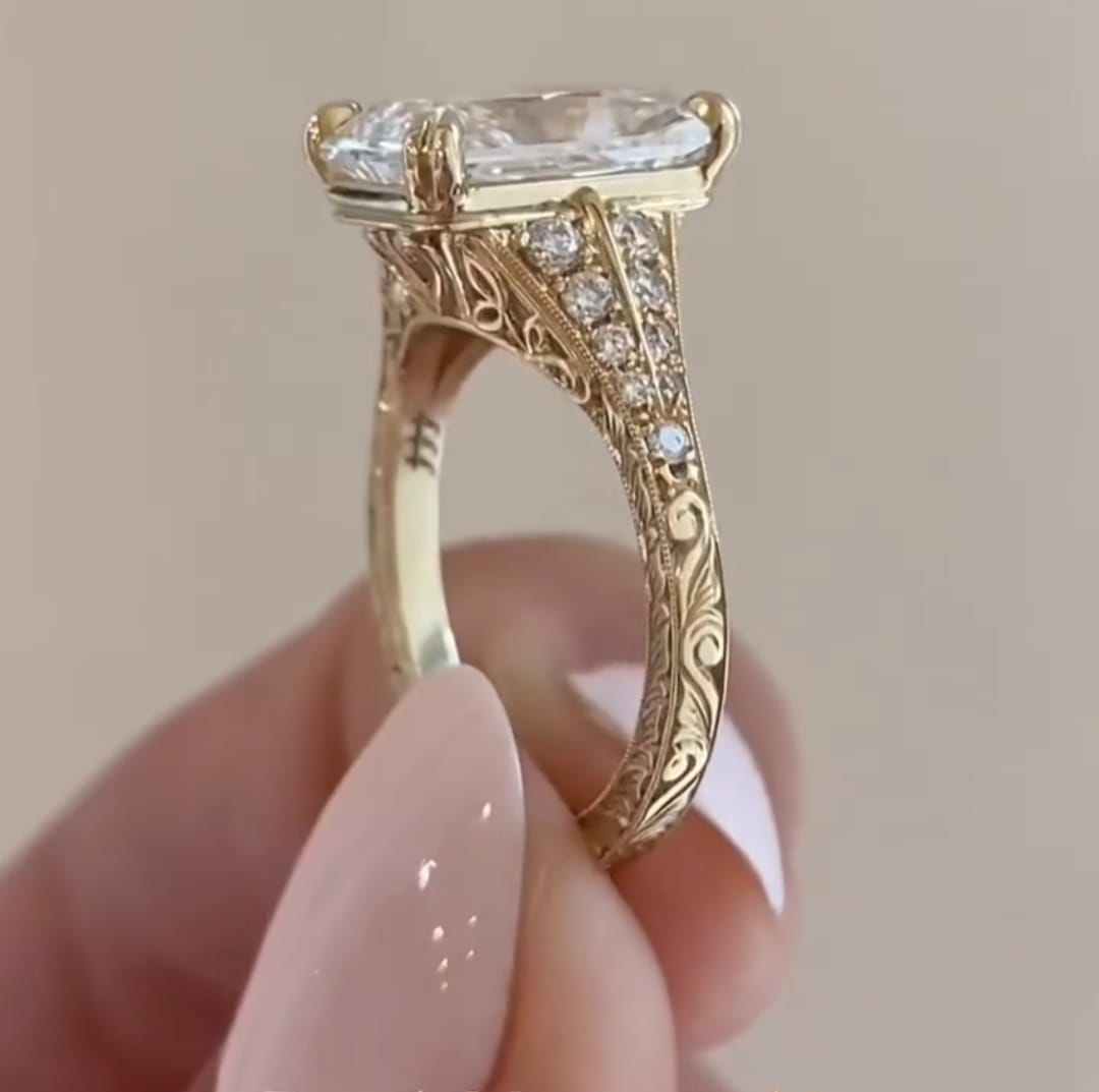 Hand-carved filigree scrollwork and pave details on the side profile of a yellow gold engagement ring.