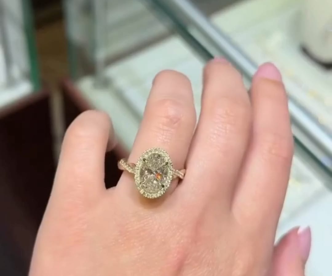Top view of 3 CT oval cut lab grown diamond halo engagement ring on hand.