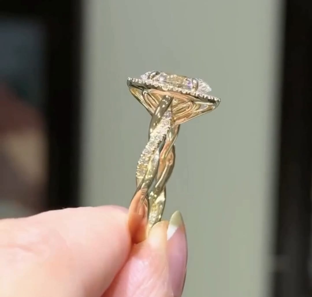 Angled view showing the intricate twist design and halo profile of an oval diamond ring.