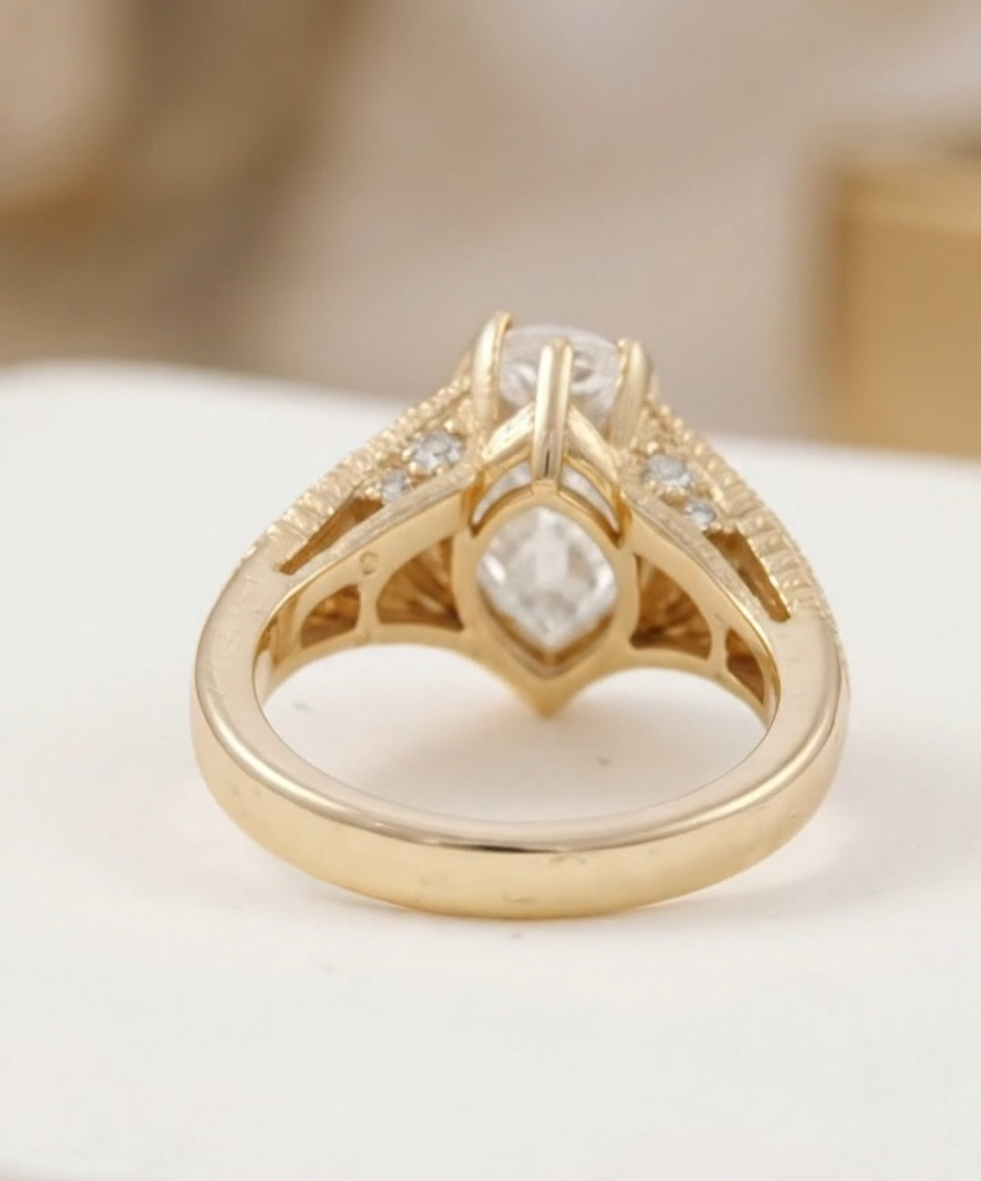 Rear profile view of a yellow gold engagement ring showing the intricate open gallery and side accent stones.