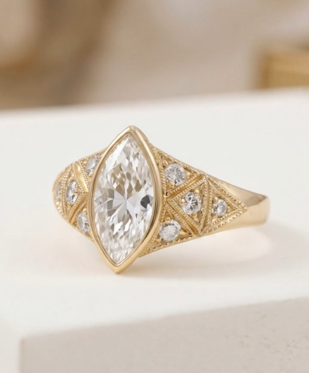 Angled top view of an Art Deco style marquise cut engagement ring in yellow gold with sparkling accent stones.