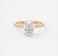 Top view of 2 carat oval cut lab grown diamond engagement ring in 14k yellow gold with pave band.