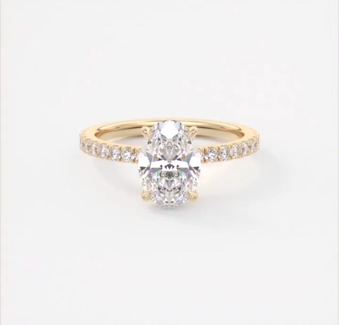 Top view of 2 carat oval cut lab grown diamond engagement ring in 14k yellow gold with pave band.