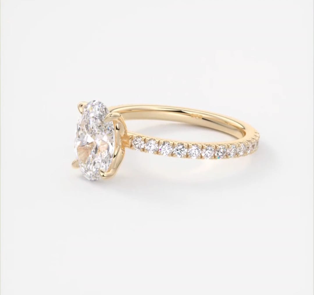 Angled shot displaying the brilliance of a 2 carat oval lab diamond in a yellow gold setting.