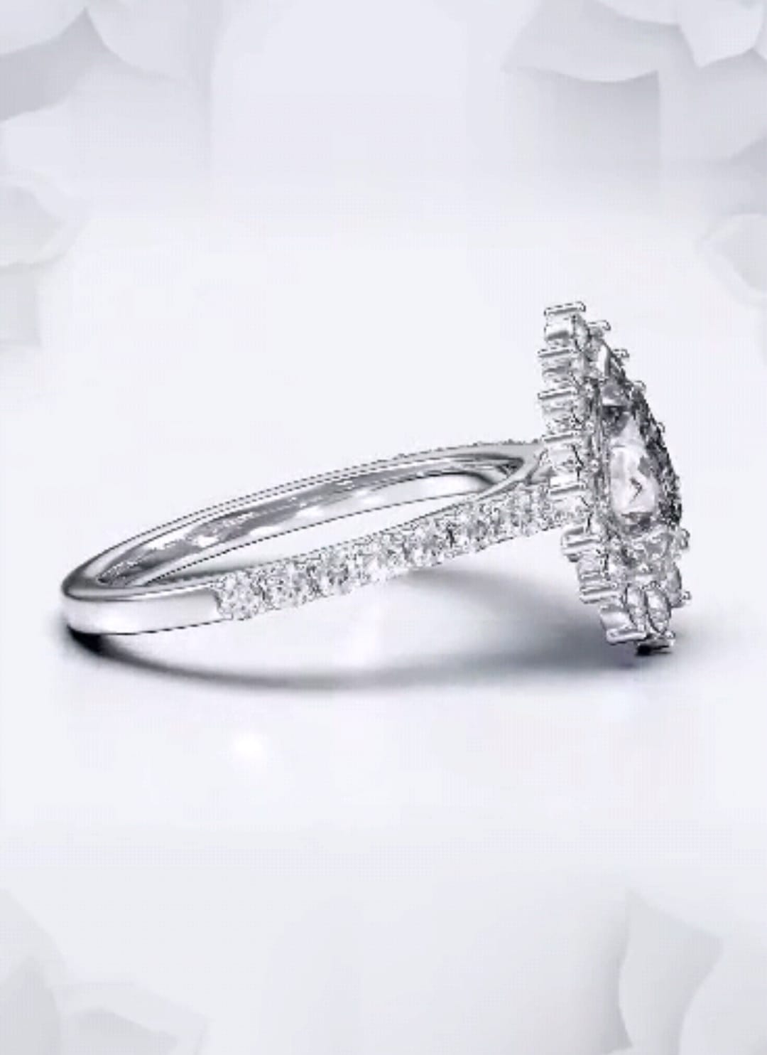 Angled shot highlighting the brilliant facets of a 2 carat pear cut lab diamond ring with a floral halo.