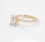 Three-quarter view of a 2 carat emerald cut lab grown diamond engagement ring in yellow gold with pavé band.