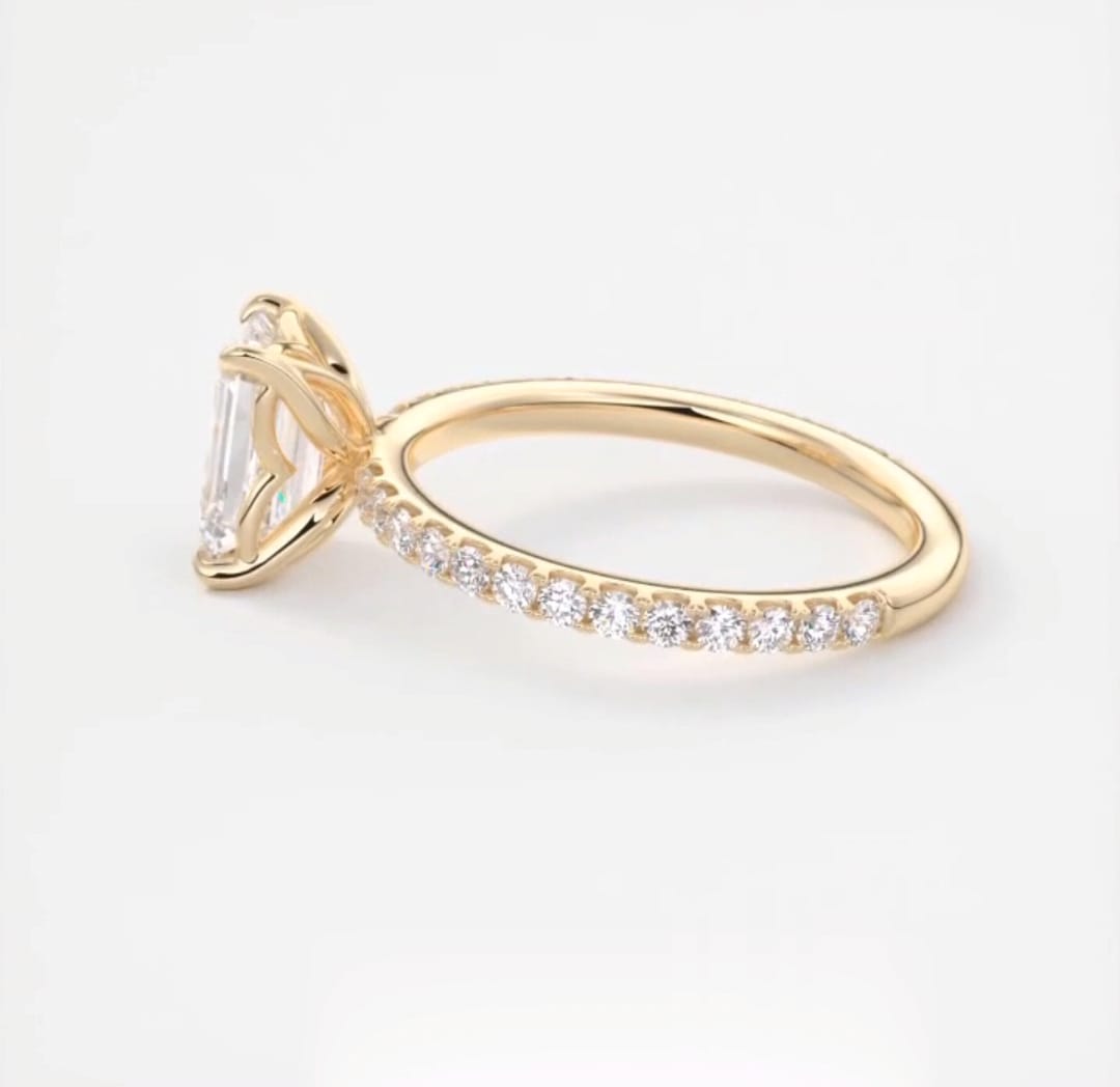 Side view showing the detailed tulip petal basket setting on a 2 CT emerald lab diamond ring.
