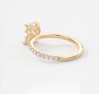 Angled back perspective displaying the micro pavé band and petal basket profile of an emerald cut ring.