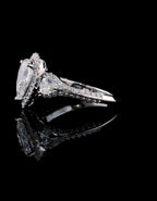 Side profile of 3 CT pear cut lab diamond ring highlighting trillion side stone and pave band construction