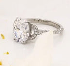 Side angle view of a 3 CT oval cut lab grown diamond engagement ring with crescent pave accents on a white surface