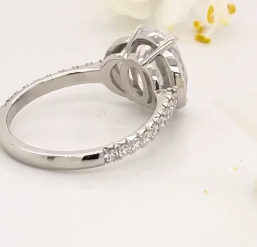 Rear angle perspective of 4-prong setting and pave band on a platinum oval lab diamond ring
