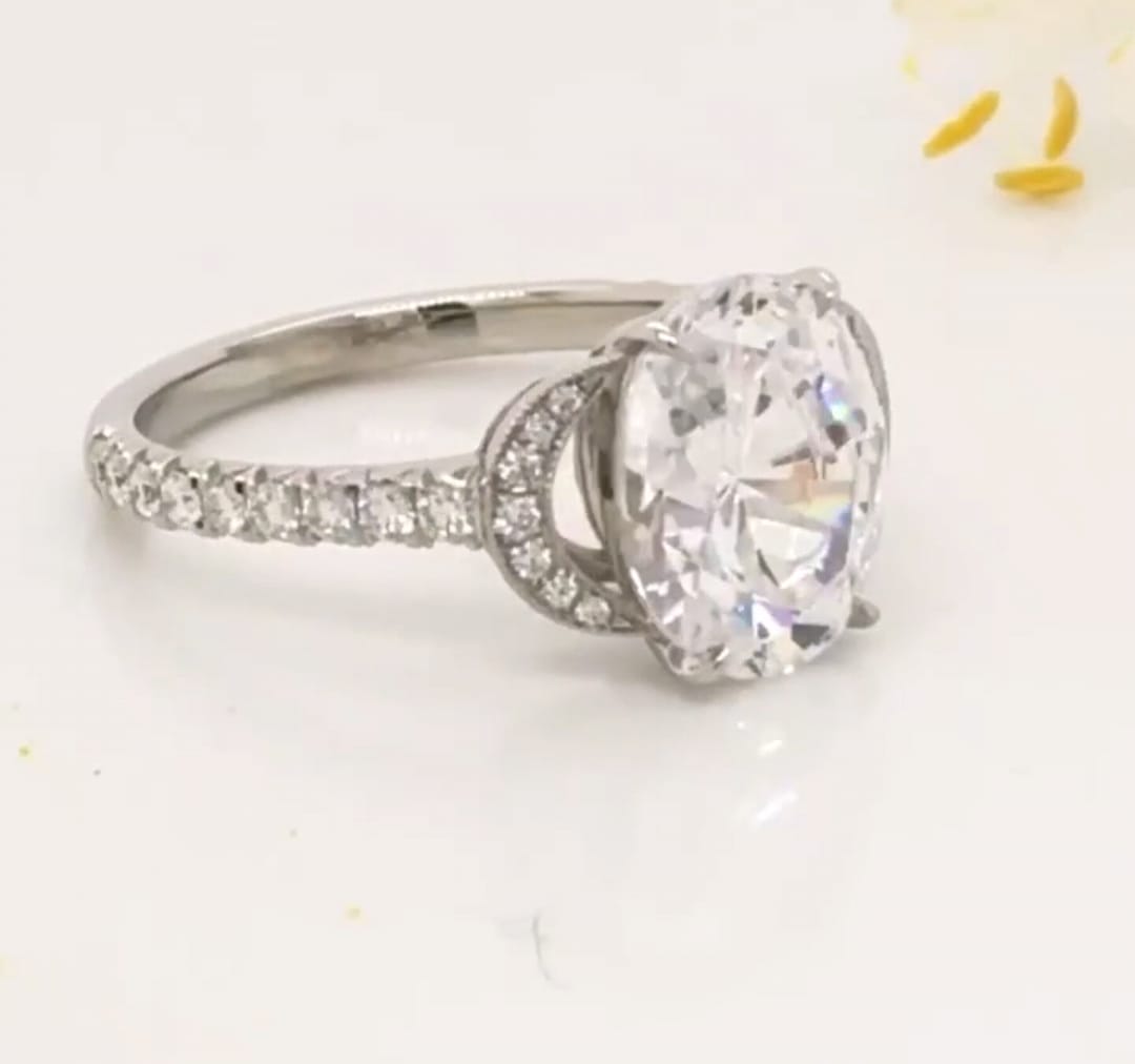Detailed angle shot displaying the curved micro-pave side motif framing a 3 CT oval cut lab diamond