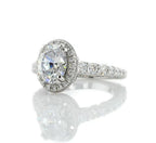 Three-quarter view of a sparkling 2 carat oval lab grown diamond with a surrounding halo and diamond band.