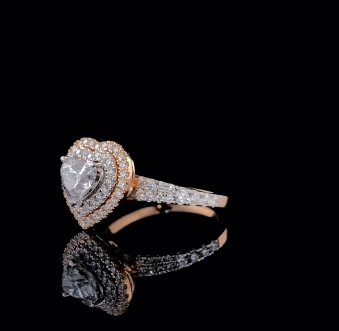 Side view of a 2 carat heart cut lab grown diamond engagement ring with a two-tone double halo and pave band on a black reflective background.