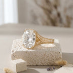 Angled top view of a cushion-cut engagement ring highlighting the deeply engraved yellow gold band and delicate claw prongs.