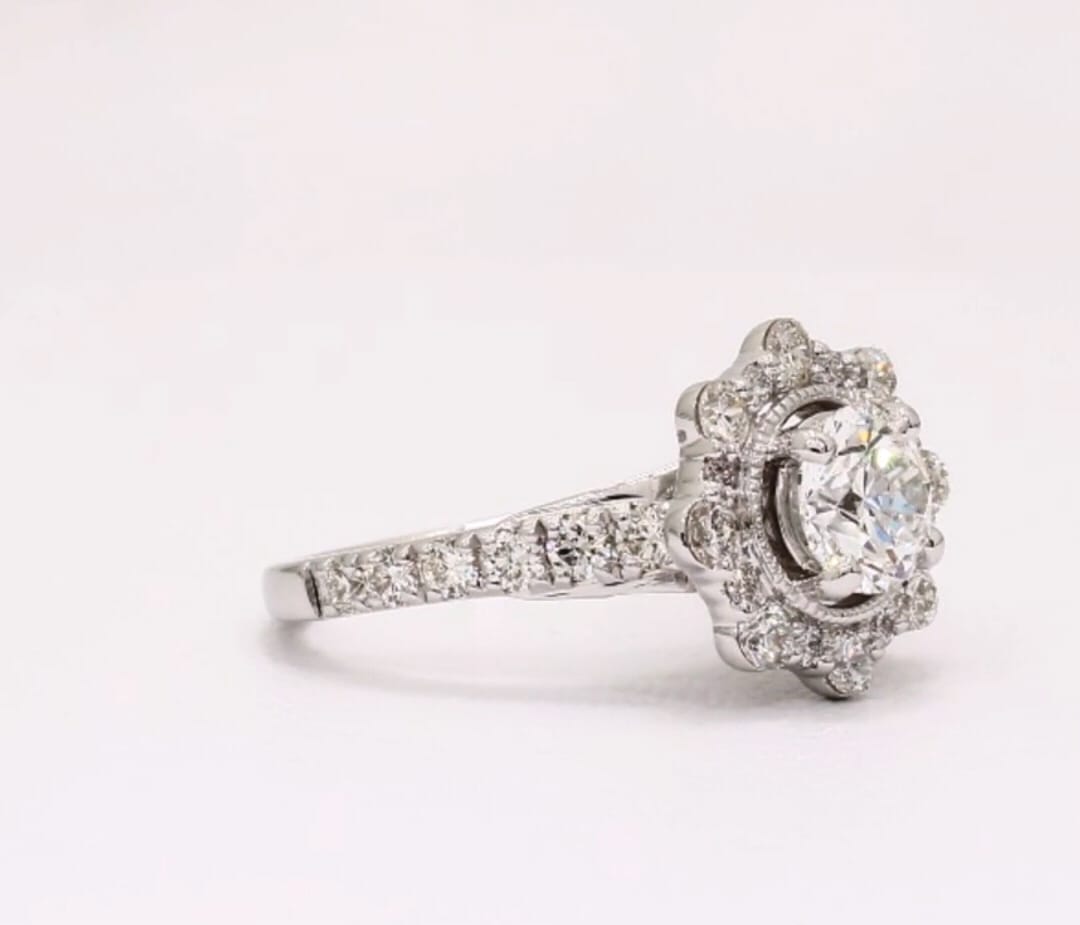 Angled view showcasing the center round diamond with milgrain bezel and floral halo