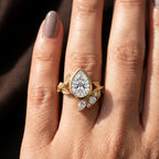 Direct overhead view of 2 carat pear cut lab diamond ring with leaf vine and cluster accents on finger.
