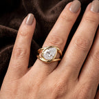 Extreme close-up of a 2 carat pear shape lab grown diamond in a modern organic bezel setting held between fingers.