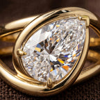 Detailed macro photo showing the facet brilliance and V-tip prong of a 2 CT pear lab diamond ring.