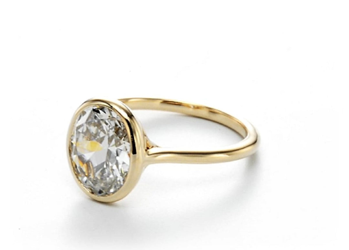 Angled front view highlighting the smooth yellow gold bezel and facet structure of a 2 CT oval lab grown diamond.
