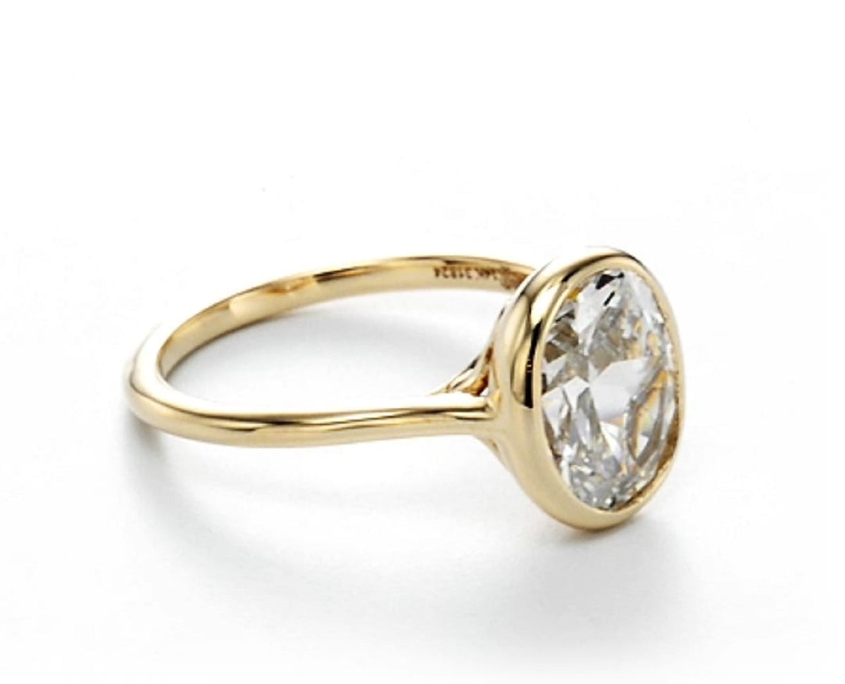 Side view showing the inner band engraving and sleek bezel head holding a 2 carat oval lab diamond.