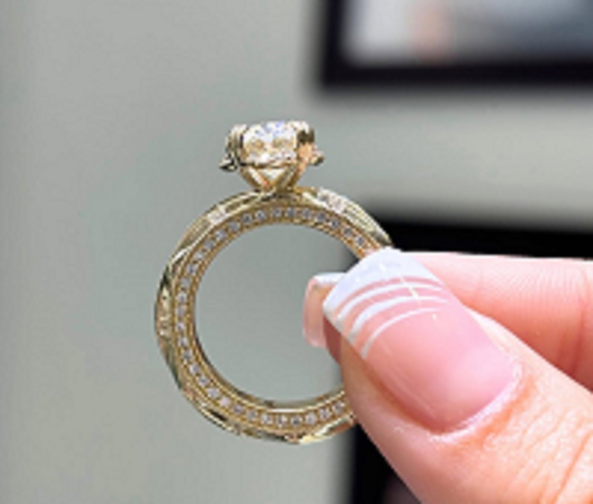 Straight-on front view of a vintage-style yellow gold engagement ring featuring a brilliant oval center stone and geometric band details.