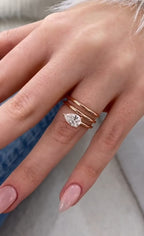 On-hand view displaying a 1.5 CT pear cut lab grown diamond ring with a modern stacked rose gold band design.