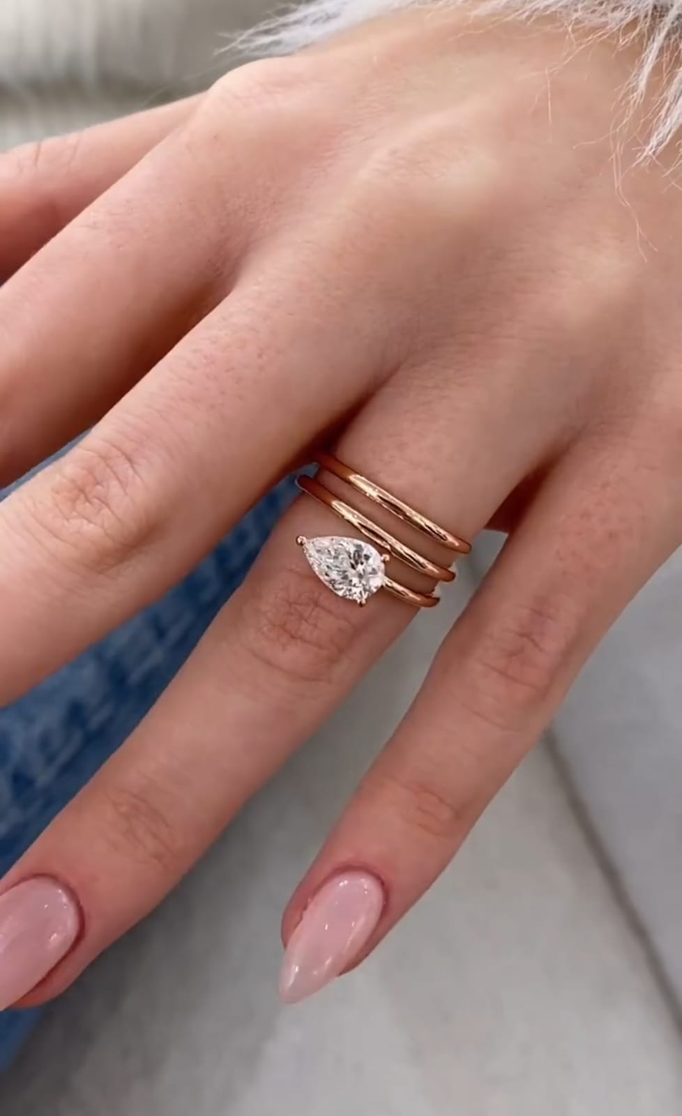 On-hand view displaying a 1.5 CT pear cut lab grown diamond ring with a modern stacked rose gold band design.