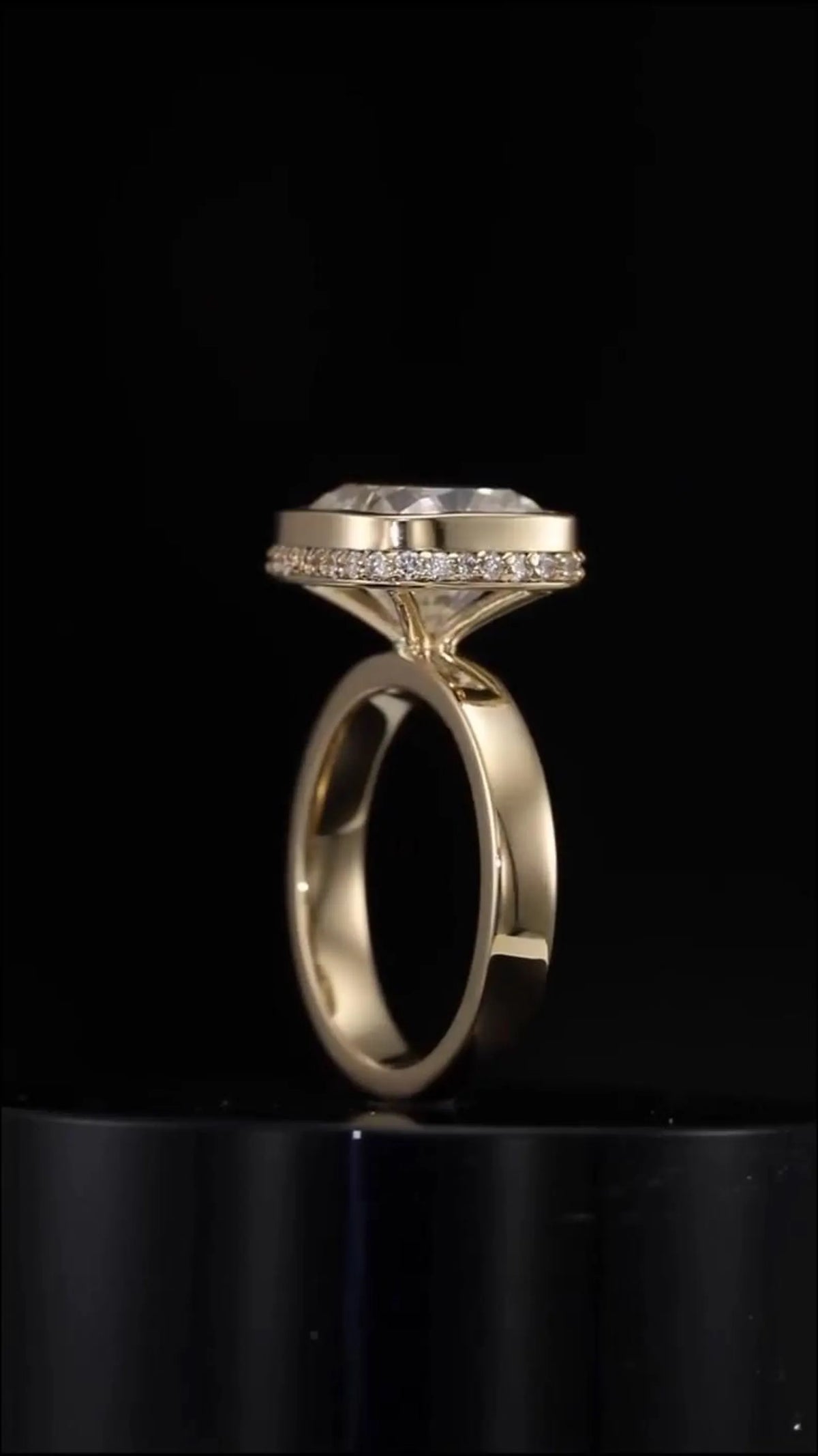 Angled side profile of yellow gold cushion cut bezel engagement ring on black background
