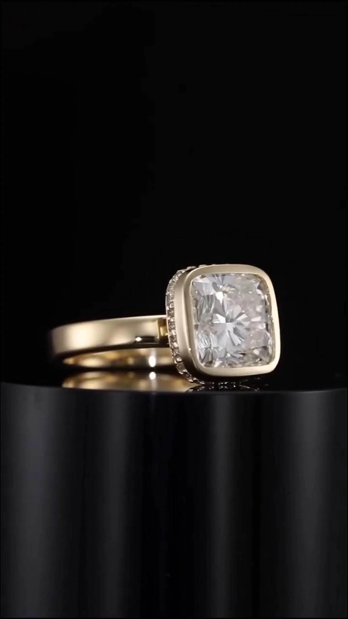 Side angle view of 3 carat cushion cut lab grown diamond bezel set ring resting on black pedestal